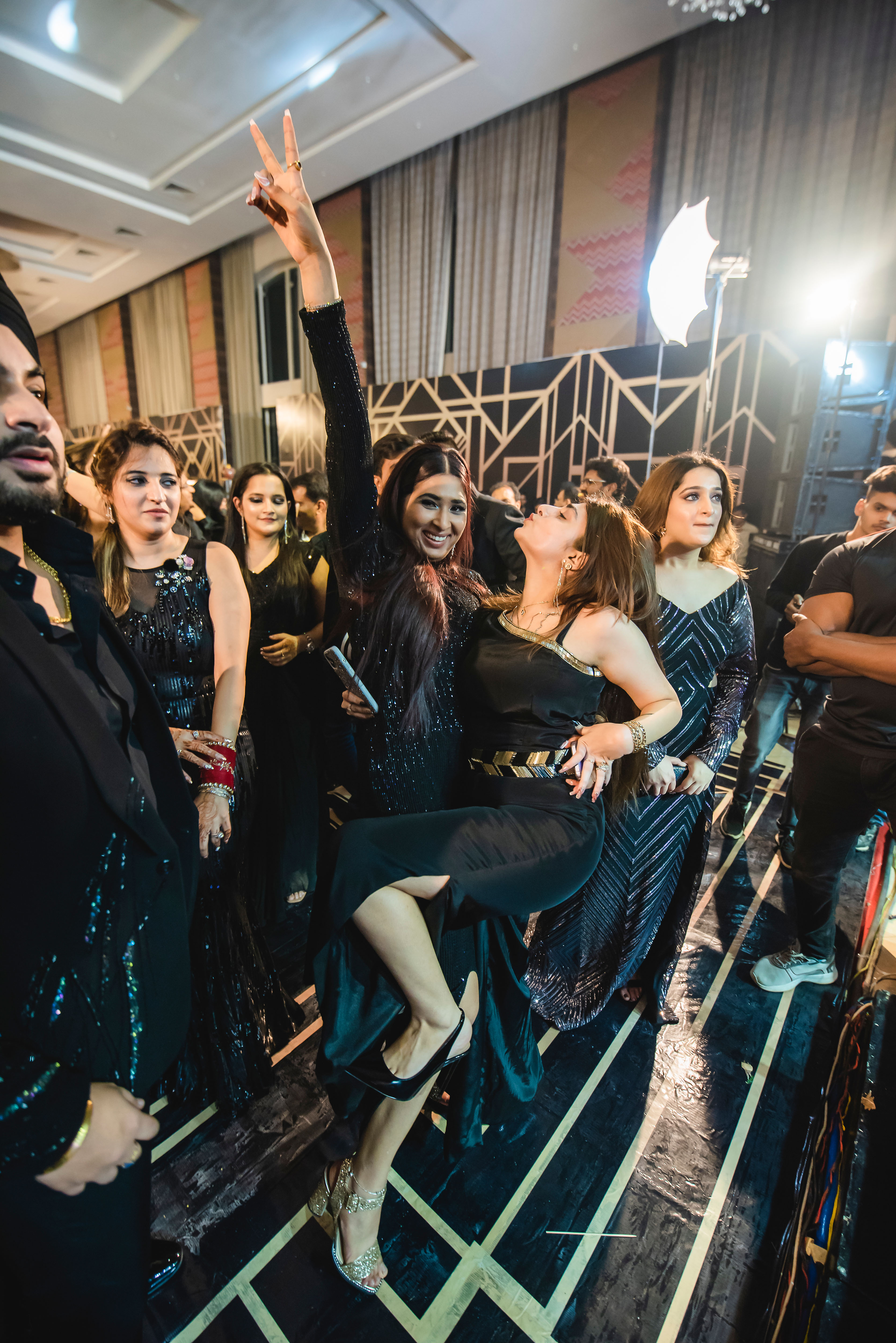 Friends in evening black, laughing together on the reception dance floor
