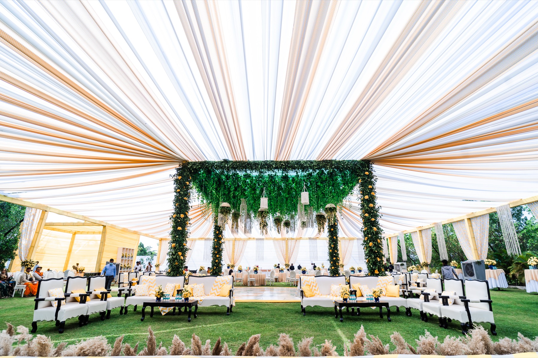 A draped reception stage and head table under hanging greenery