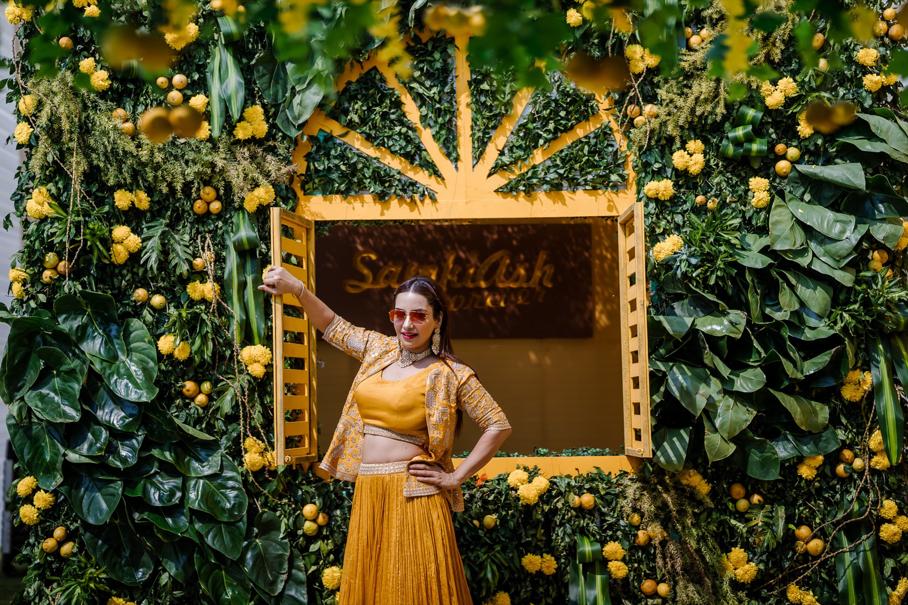 Bride in a yellow lehenga before a marigold haldi backdrop