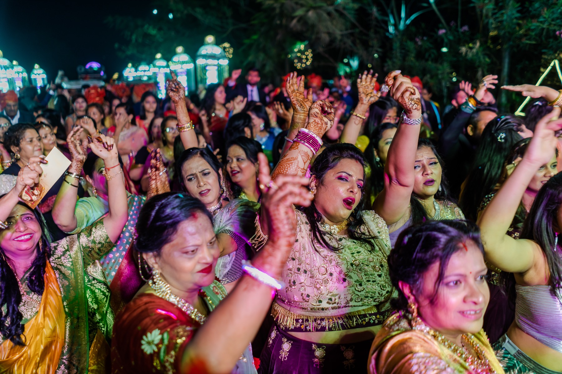 A crowd of women dancing in colourful sarees at night