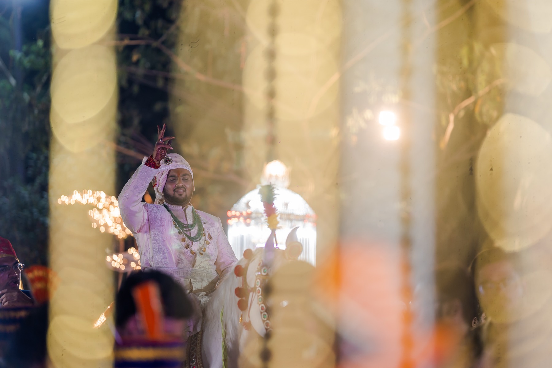 Groom in a sehra arriving amid sparklers