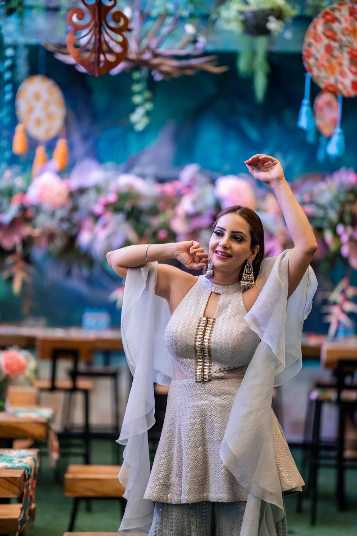 A guest dancing in white before a floral dreamcatcher backdrop