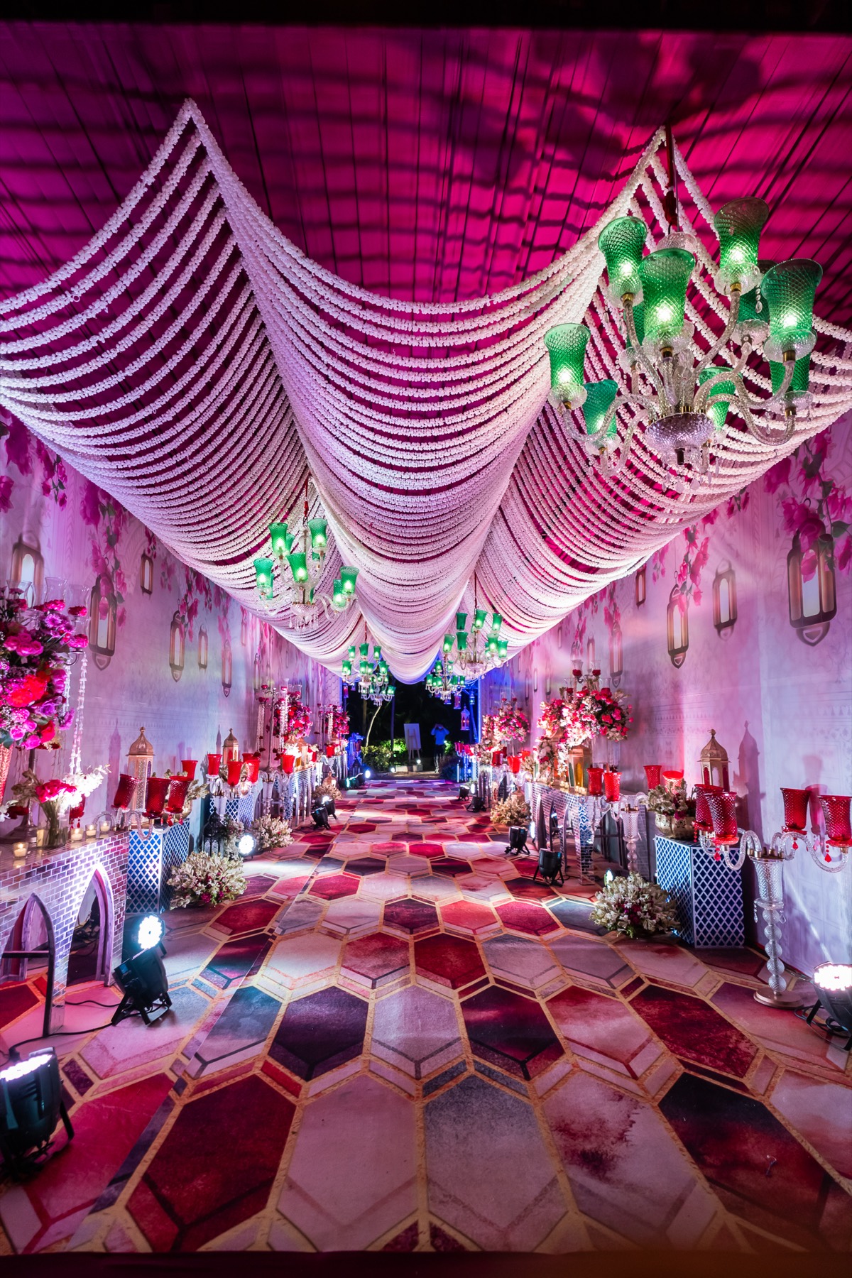 A draped pink ceiling above a decorated aisle