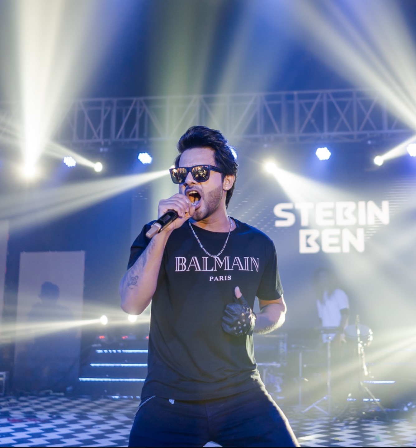 Singer performing live on stage with dramatic concert lighting